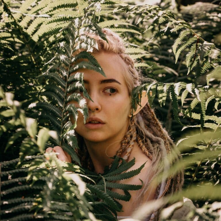The times I didn't die: A woman's face part visible through a curtain of leaves