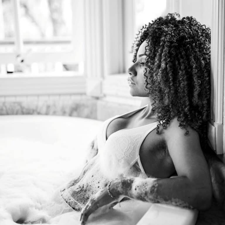 ADHD shower: a black and white photo of a woman sitting in a bath, leaning backwards.