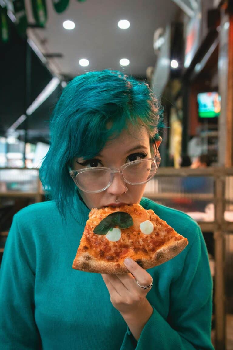 ADHD food hacks: it doesn't have to be difficult. Pictured: a woman with green hair eating pizza.