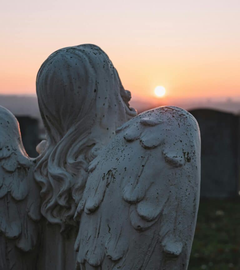 Angel statue at sunset in a cemetery, symbolizing grief, loss, and quiet reflection in neurodivergent grieving experiences